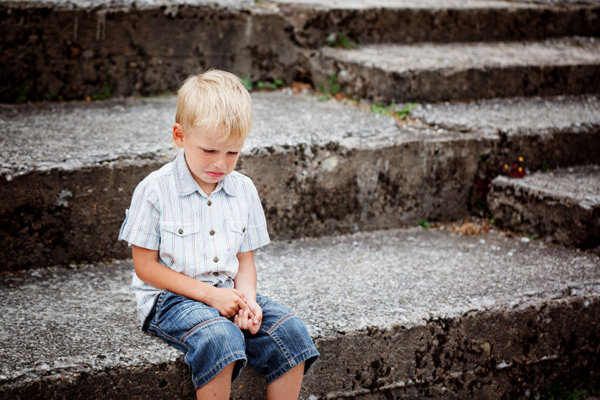 Little Boy crying sitting on stone steps in park Loneliness melancholy stress