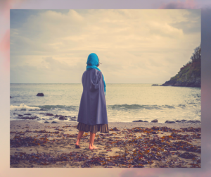 Young Barefoot Woman with Headscarf on Beach looking and grieving her losses and hoping for a secure future